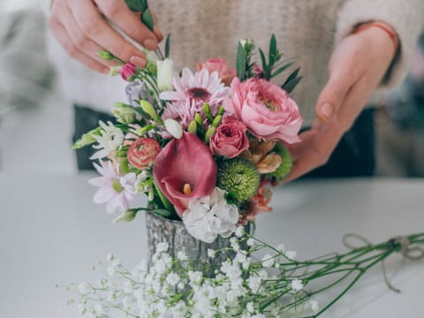 A florist's hands shaping an arrangement of pink flowers.