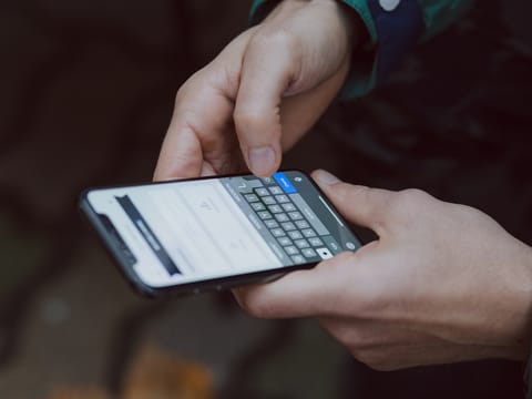 Two hands holding a phone, reading a new message.