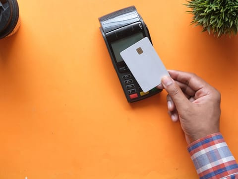 A hand holding a bank card at a payment terminal.